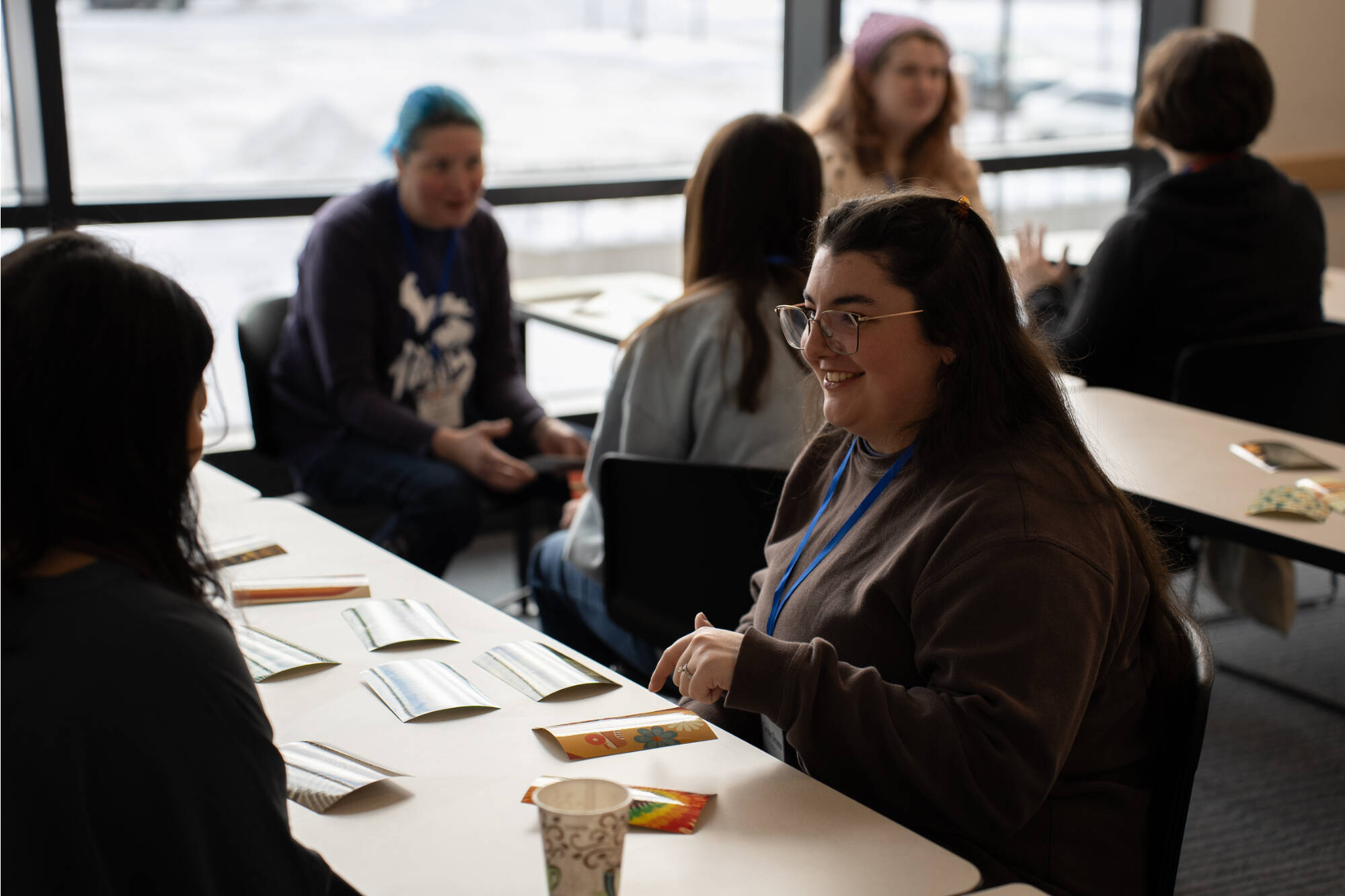 A student pointing to a printed photo and smiling while chatting with another student